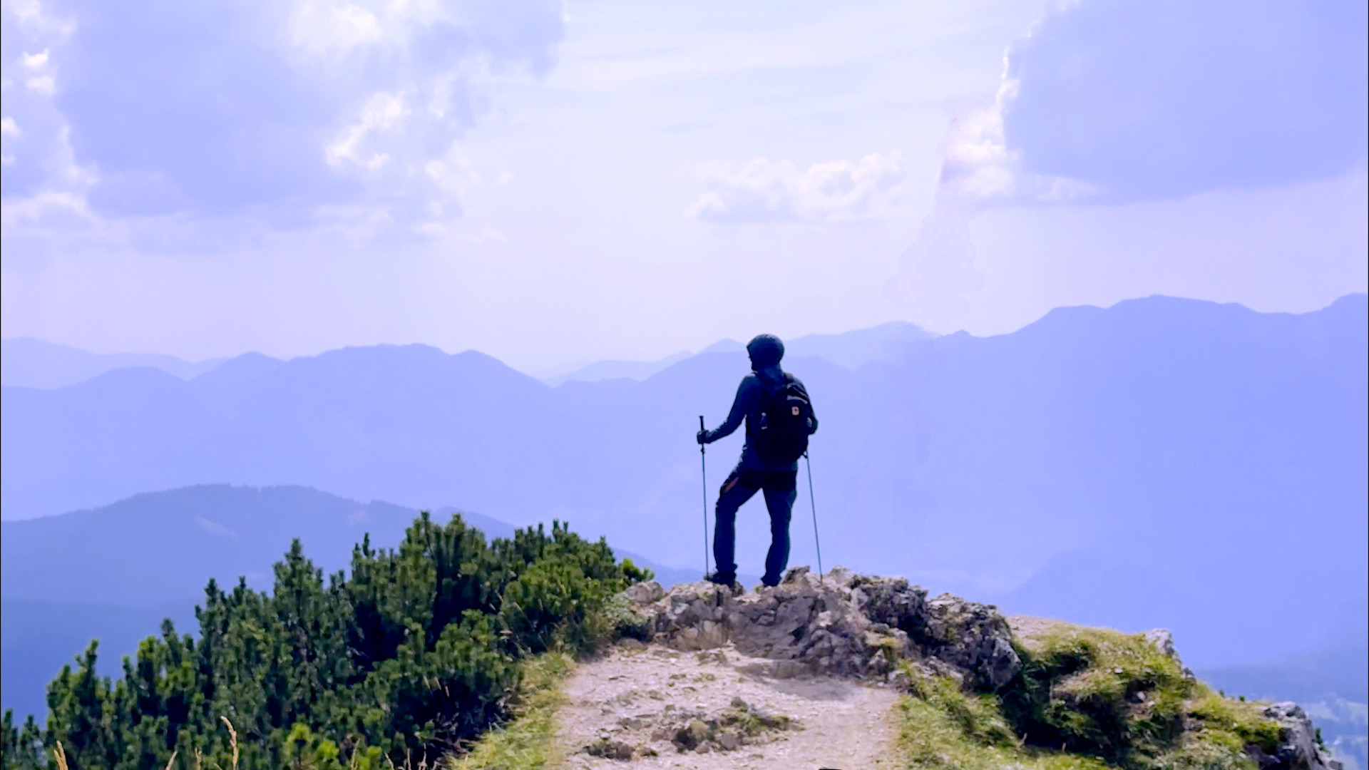 Photography of a intermediary summit, with misty mountains in the background and me looking at them from the local summit