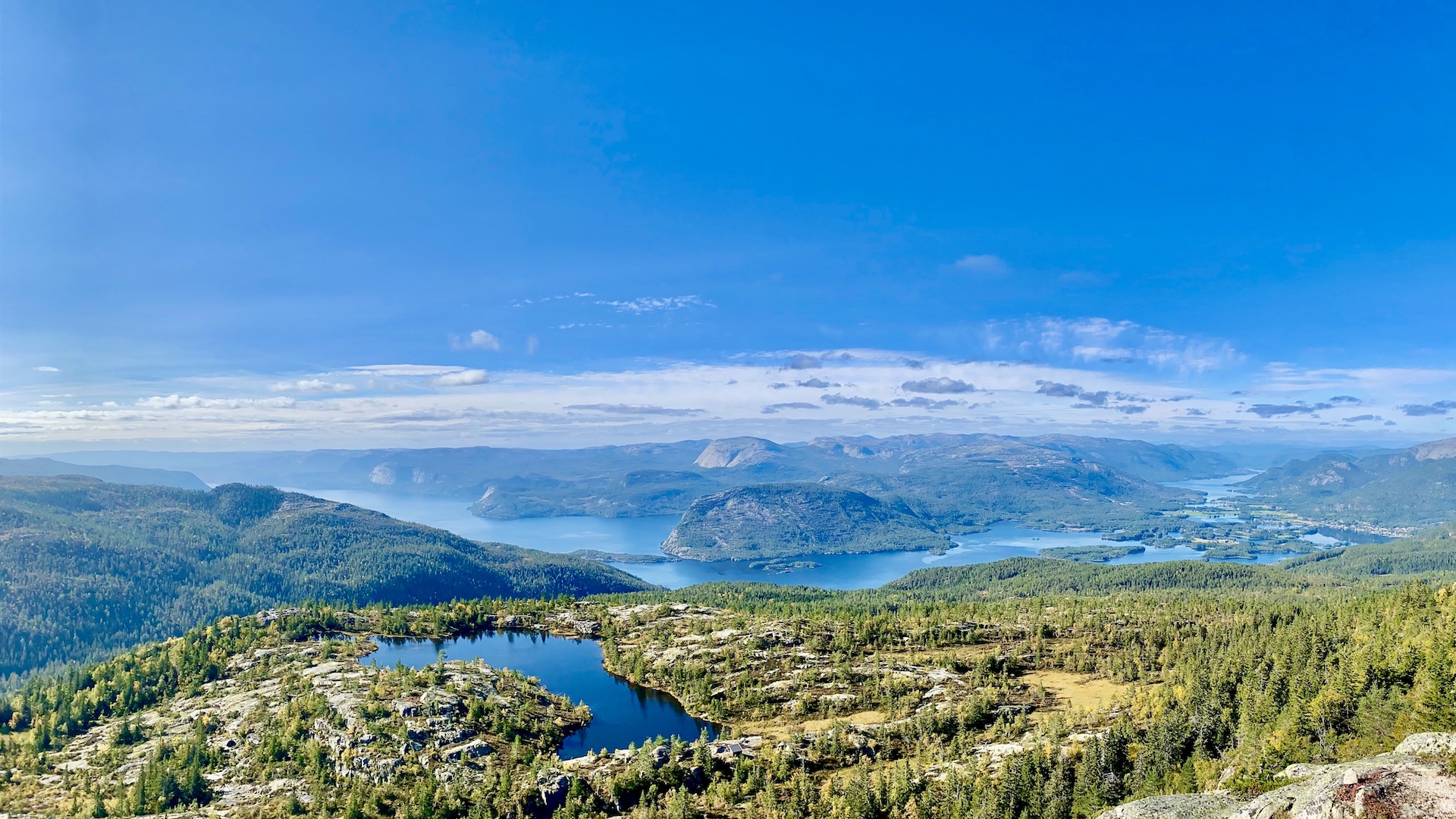Photography of the panoramic views from the summit, multiple blue lakes, mountains all around, and small houses here and there far below